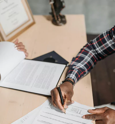 Person signing official papers on a desk.