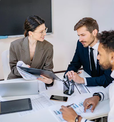 Three people reviewing data charts at a table.